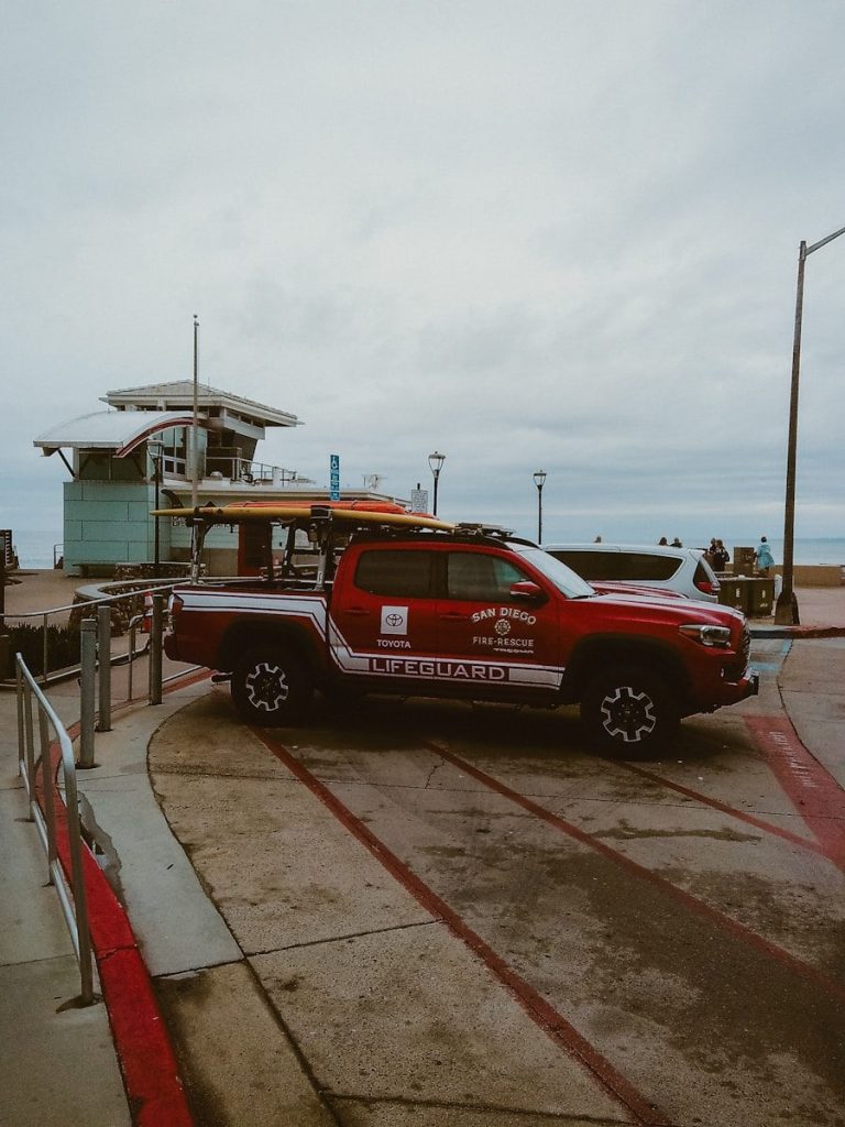Red lifeguard truck parked near a lifeguard station.