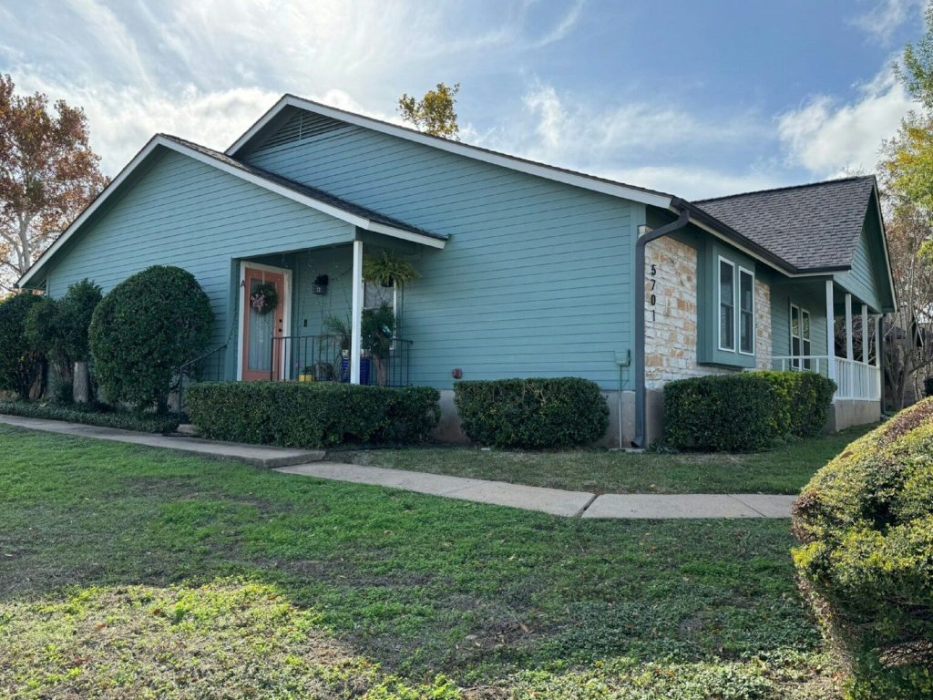 A teal house with stone accents and green lawn.