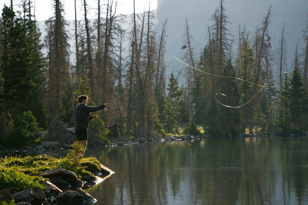 A man standing on top of a lush green field next to a lake