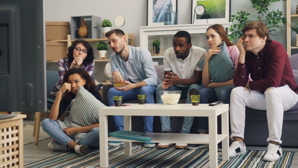 A group of friends enjoying a movie night together indoors with snacks and drinks.