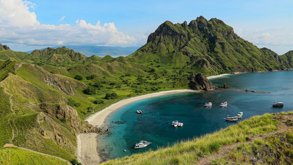 Explore the picturesque bay of Padar Island with its lush hills and turquoise waters.