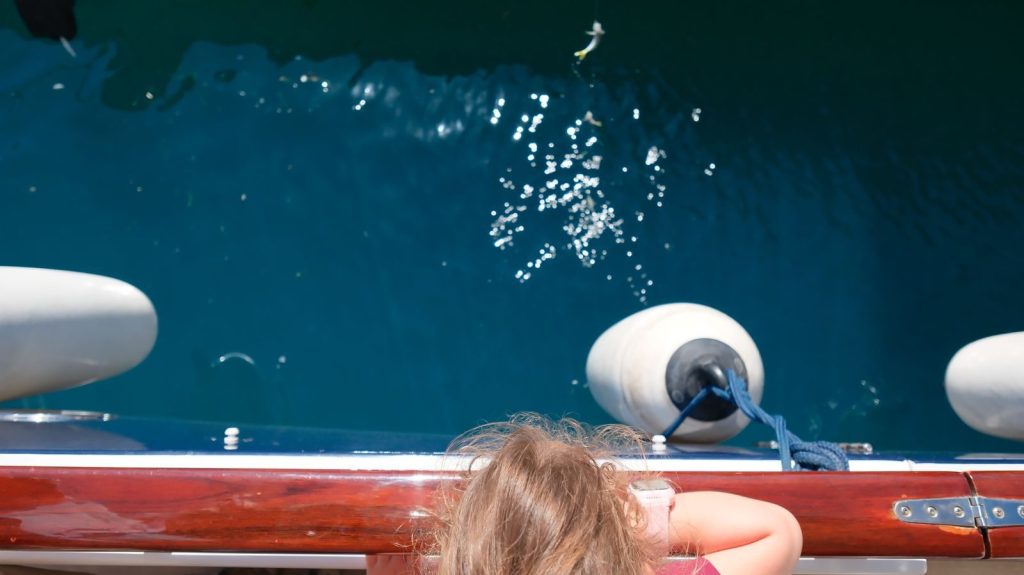 A child gazes at the shimmering sea from a boat in Istanbul, enjoying a sunny day outdoors.