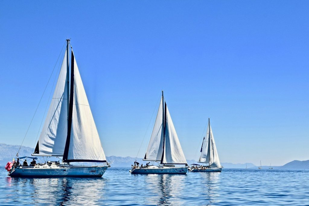 three sail boats on water during daytime