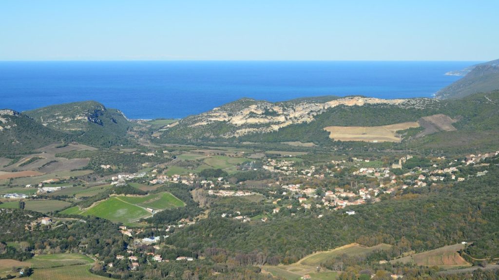 Coastal town nestled between green hills and blue sea
