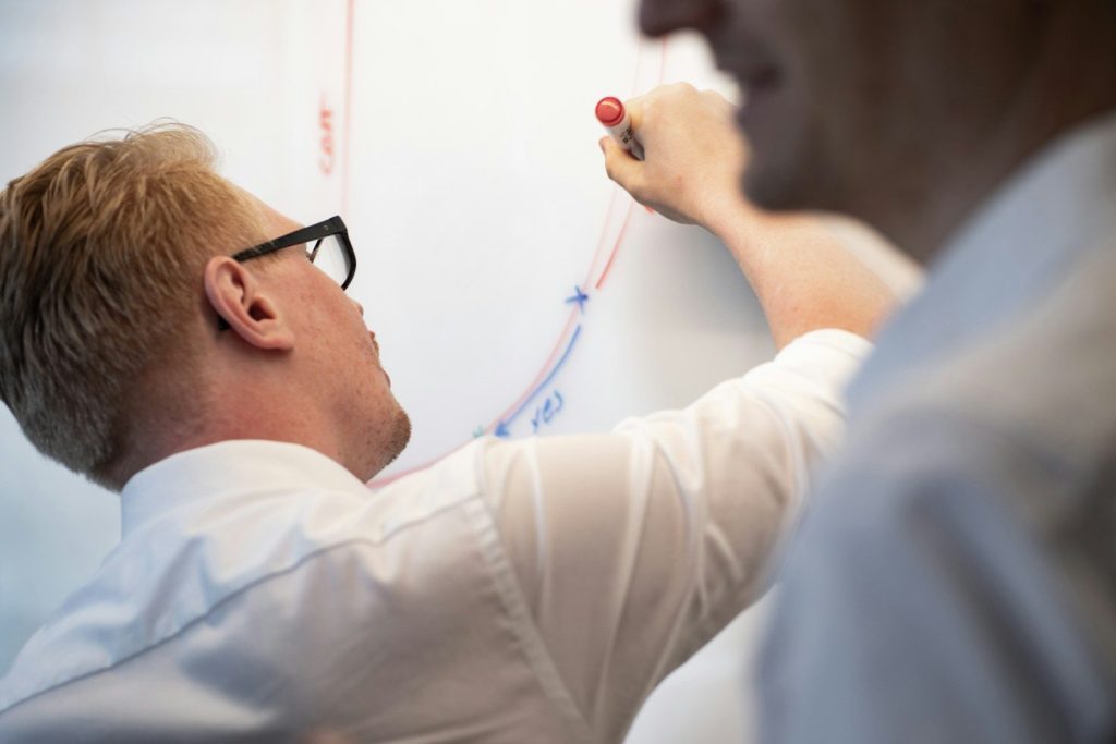 a man writing on a whiteboard with a marker