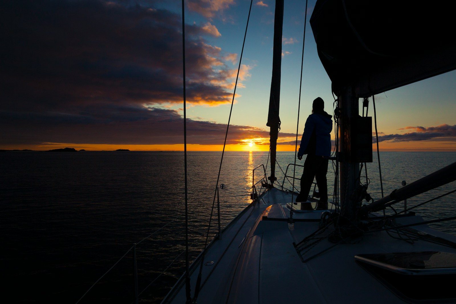 a person standing on the deck of a boat at sunset