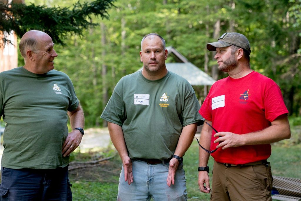 Three men in casual outdoor clothing talking
