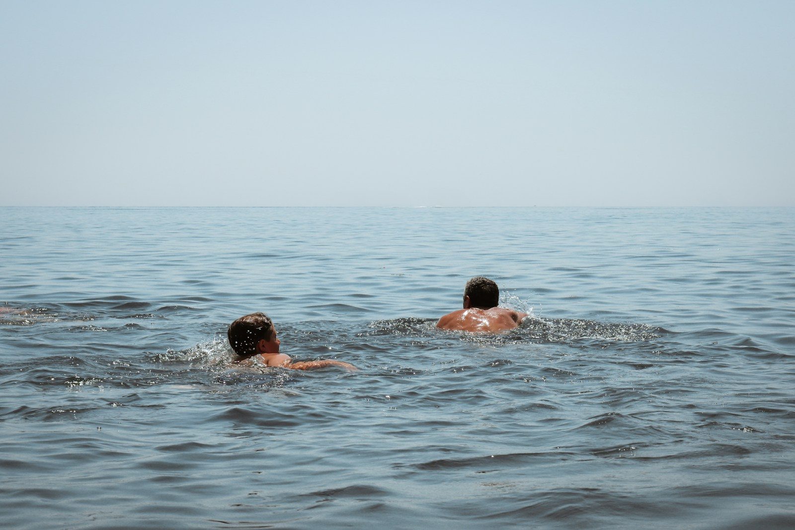 Two people swimming in the calm ocean.