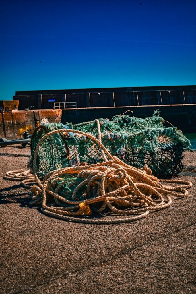 Fishing nets and ropes sit on a pier.