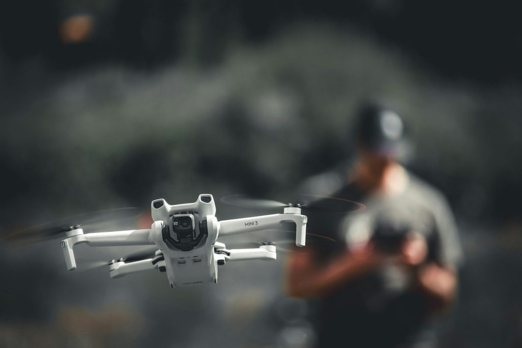a man holding a white and black remote control flying a white and black remote control