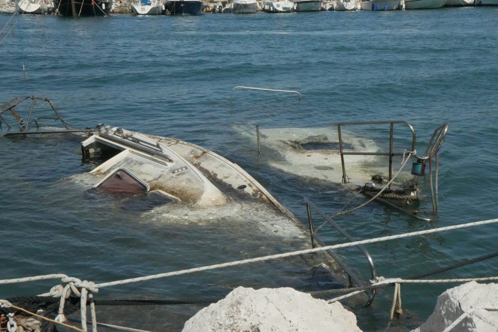 Partially submerged boat in a harbor with other boats.
