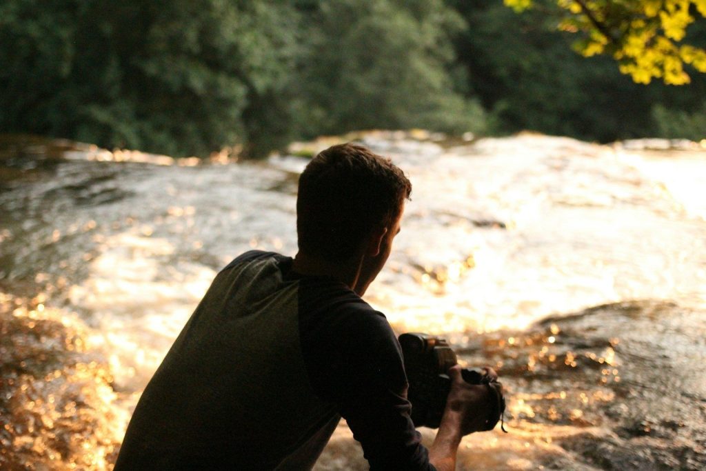 man in black jacket holding black dslr camera