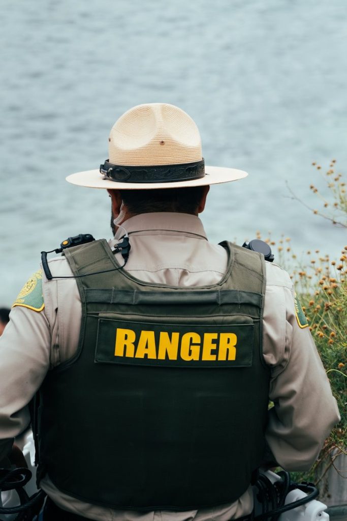 A park ranger wearing a uniform looks towards the ocean.