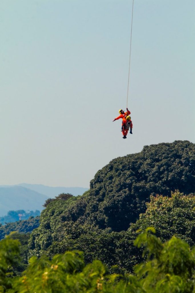 Rescuer rappels with person down from helicopter