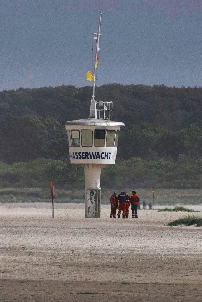 Lifeguard tower on a sandy beach with people.