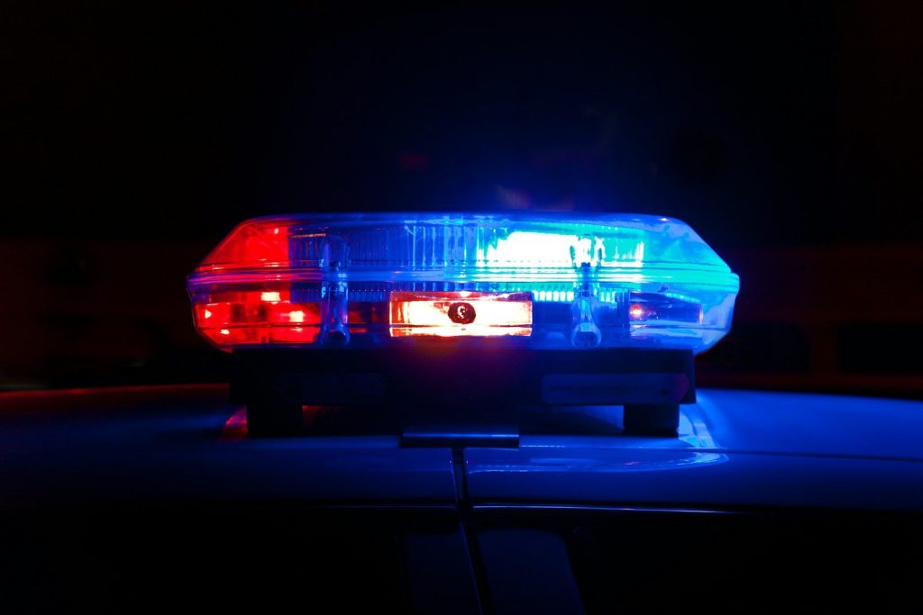 A police light bar flashing red and blue against a dark night background