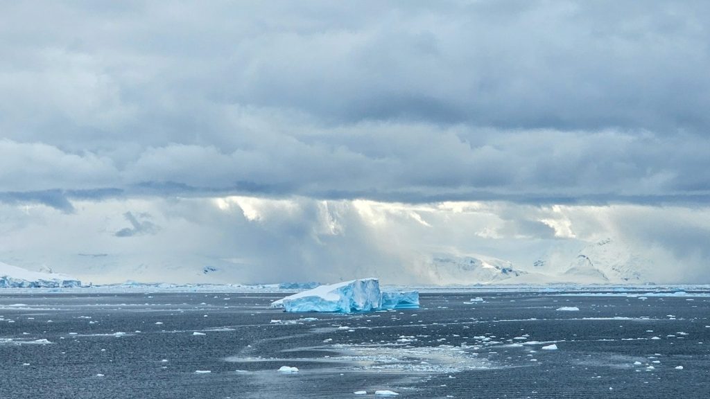 Iceberg floating in the ocean under cloudy sky